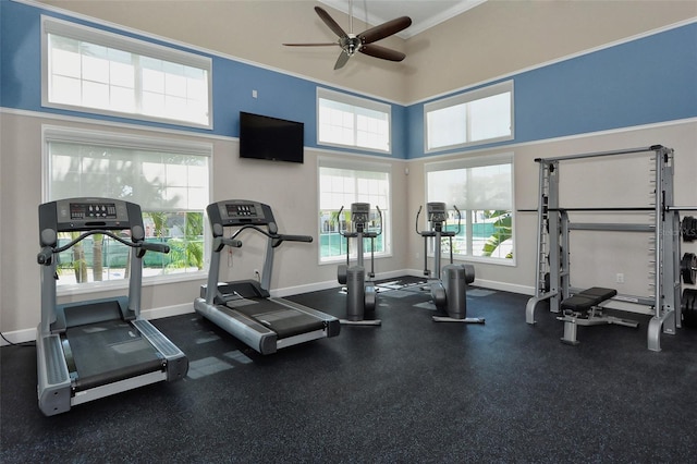 workout area with crown molding, a ceiling fan, and baseboards