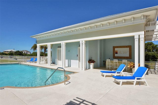 pool featuring a patio, fence, and outdoor dry bar