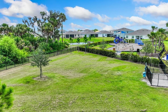 view of yard featuring fence, playground community, and a residential view