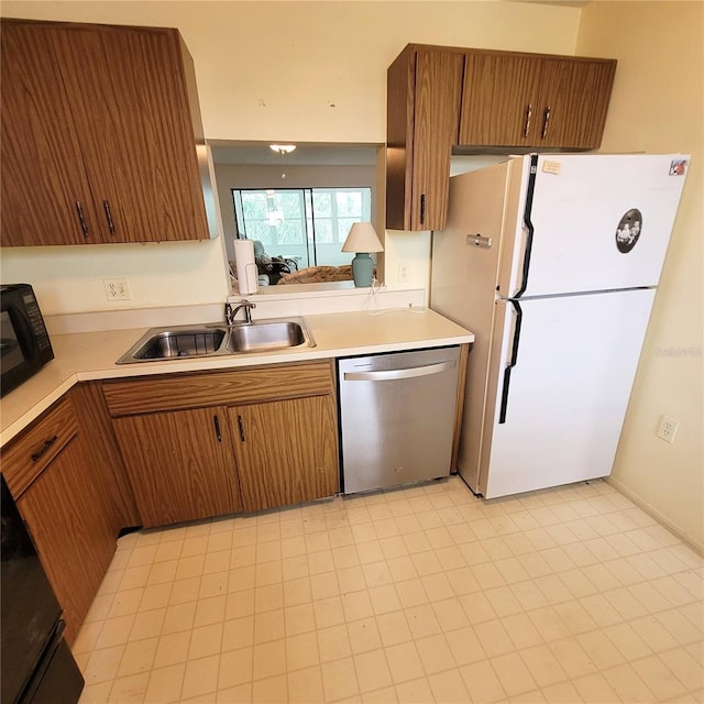 kitchen featuring a sink, freestanding refrigerator, black microwave, light countertops, and dishwasher