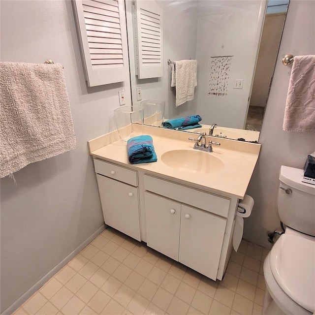 bathroom with toilet, vanity, and baseboards