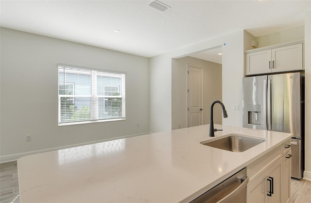 kitchen with visible vents, a sink, white cabinetry, appliances with stainless steel finishes, and light wood finished floors