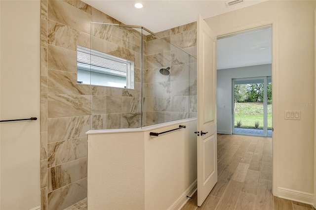 bathroom with a wealth of natural light, baseboards, walk in shower, and wood finished floors