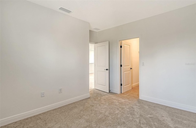 unfurnished room with visible vents, baseboards, and light colored carpet