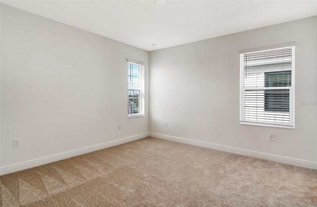 spare room with light colored carpet and baseboards