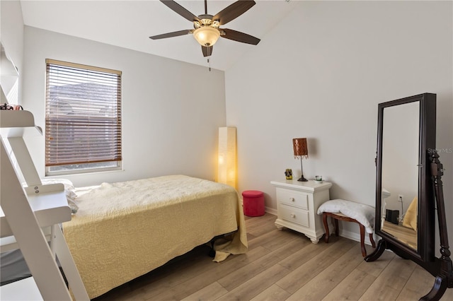 bedroom featuring ceiling fan, baseboards, light wood-style floors, and vaulted ceiling
