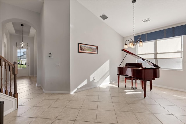 foyer with a notable chandelier, light tile patterned flooring, visible vents, and arched walkways