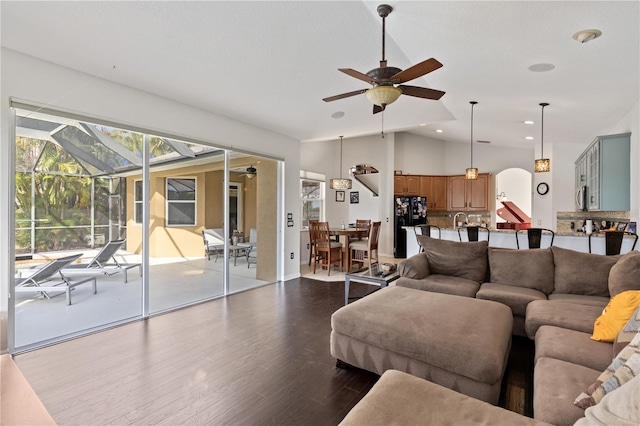living area featuring a ceiling fan, dark wood finished floors, lofted ceiling, recessed lighting, and arched walkways