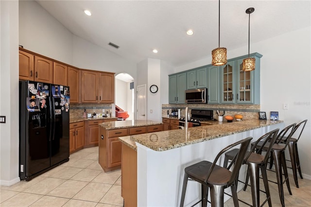 kitchen featuring visible vents, light stone counters, stainless steel appliances, a peninsula, and lofted ceiling