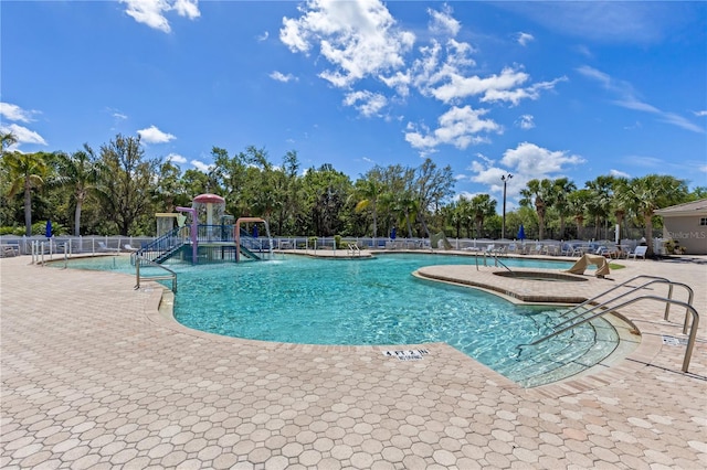 pool with a patio, fence, and playground community