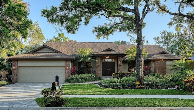 ranch-style home with decorative driveway, brick siding, a garage, and a front yard