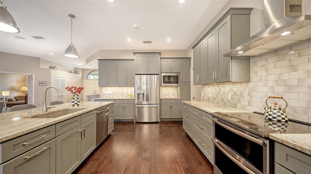 kitchen with a sink, stainless steel appliances, gray cabinetry, and wall chimney exhaust hood