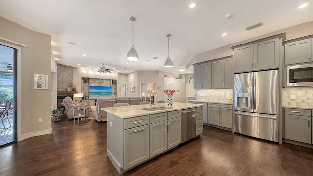 kitchen with a ceiling fan, a sink, gray cabinetry, appliances with stainless steel finishes, and backsplash