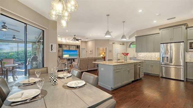 kitchen with decorative backsplash, gray cabinets, stainless steel appliances, and ceiling fan