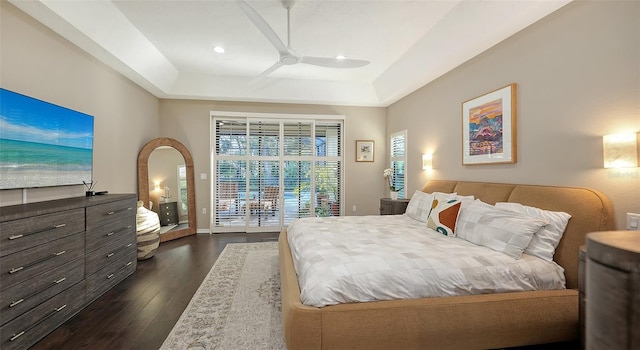 bedroom featuring a ceiling fan, dark wood-style floors, baseboards, a raised ceiling, and access to outside