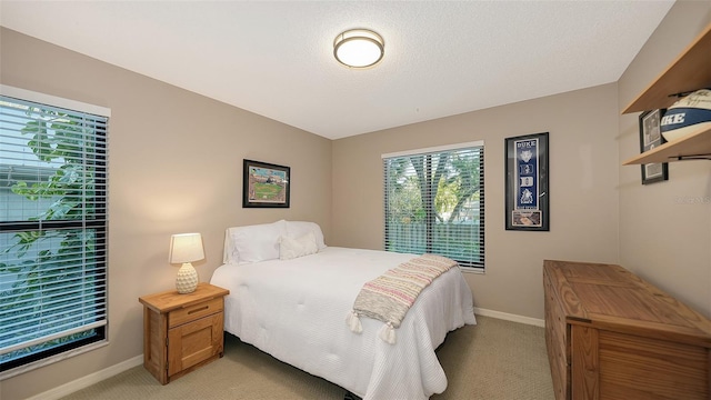 bedroom featuring a textured ceiling, baseboards, and light carpet