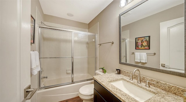 full bath with toilet, vanity, and bath / shower combo with glass door