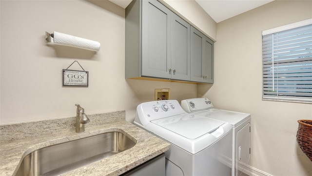 clothes washing area with cabinet space, independent washer and dryer, and a sink