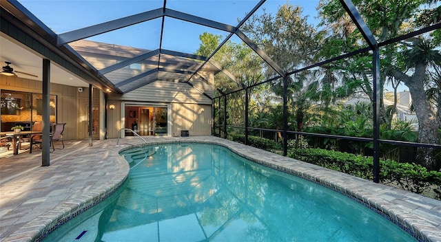 outdoor pool featuring glass enclosure, a patio, and a ceiling fan