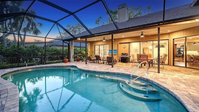 outdoor pool with glass enclosure, a ceiling fan, and a patio