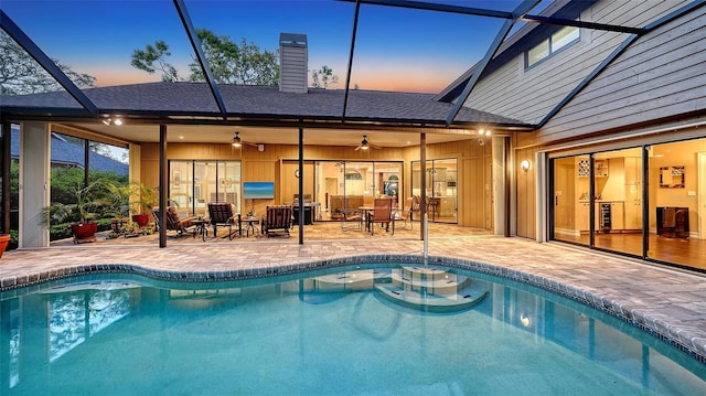 pool with a patio area, glass enclosure, and a ceiling fan