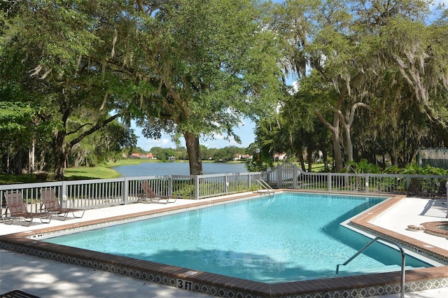 pool with a patio area, fence, and a water view