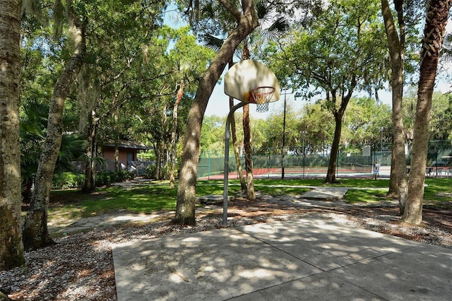 view of community with a tennis court, community basketball court, and fence