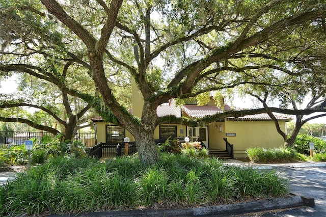 view of front of home with stucco siding, fence, and a tile roof