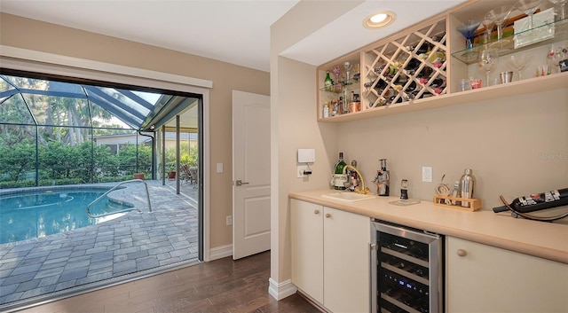 bar featuring baseboards, wine cooler, dark wood-style floors, a bar, and a sink