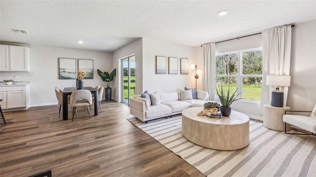 living area with baseboards, visible vents, light wood-style flooring, recessed lighting, and a textured ceiling