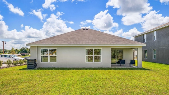 rear view of property with stucco siding, a yard, cooling unit, a shingled roof, and a patio area