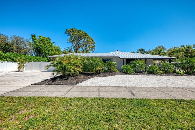 exterior space featuring metal roof, driveway, and fence