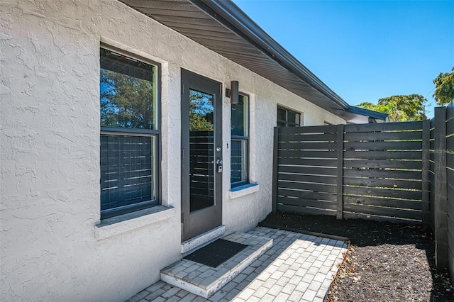 property entrance featuring stucco siding and fence