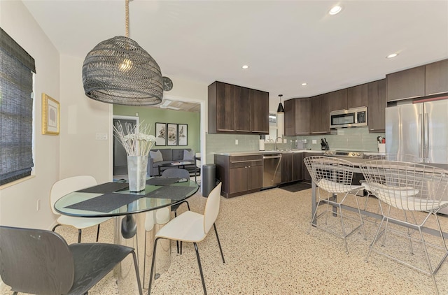 kitchen featuring recessed lighting, decorative backsplash, dark brown cabinetry, and appliances with stainless steel finishes