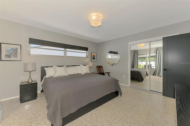 bedroom featuring baseboards, speckled floor, and a closet