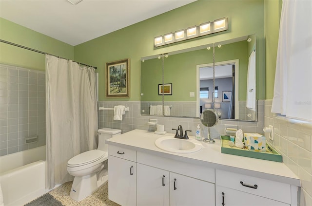 full bathroom with a wainscoted wall, toilet, vanity, shower / tub combo with curtain, and tile walls