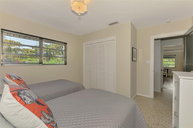 bedroom with visible vents, light speckled floor, baseboards, and a closet