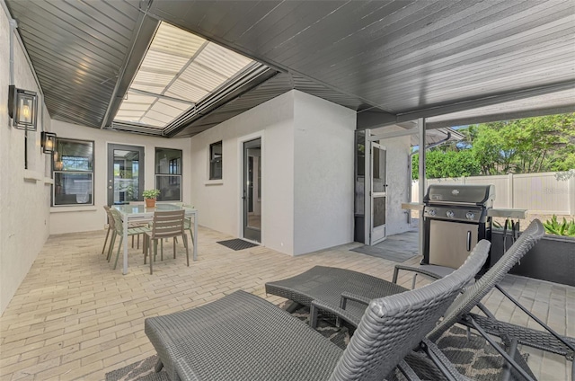 view of patio featuring grilling area, outdoor dining space, and fence