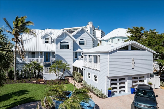 137 Big Pass Ln, Sarasota, FL 34242 - back of house with a standing seam roof, an attached garage, a balcony, metal roof, and decorative driveway