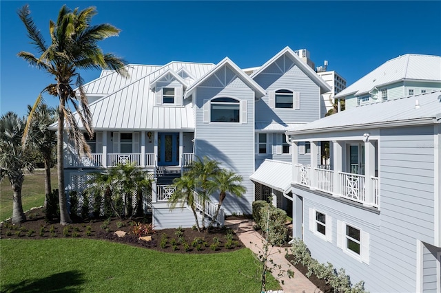 137 Big Pass Ln, Sarasota, FL 34242 - rear view of house with covered porch, stairway, a yard, and metal roof