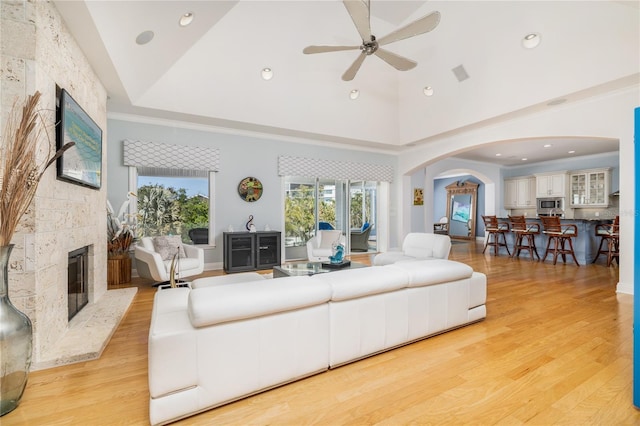 137 Big Pass Ln, Sarasota, FL 34242 - living room featuring light wood-type flooring, high vaulted ceiling, arched walkways, a ceiling fan, and a fireplace
