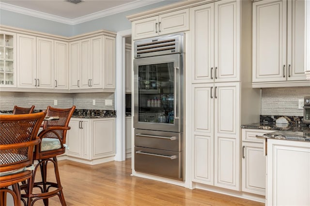 137 Big Pass Ln, Sarasota, FL 34242 - kitchen featuring crown molding, light wood-style flooring, backsplash, and dark stone countertops