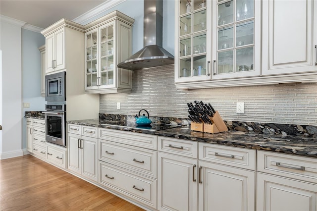 137 Big Pass Ln, Sarasota, FL 34242 - kitchen with backsplash, appliances with stainless steel finishes, wall chimney range hood, light wood-style floors, and ornamental molding