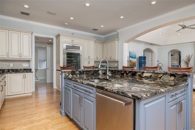 137 Big Pass Ln, Sarasota, FL 34242 - kitchen with ornamental molding, a sink, an island with sink, light wood finished floors, and dishwasher