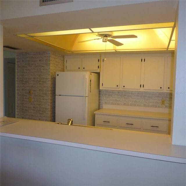 kitchen with light countertops, white cabinets, a ceiling fan, and freestanding refrigerator