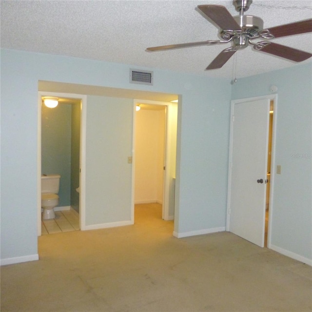 unfurnished bedroom featuring carpet, baseboards, visible vents, ensuite bath, and a textured ceiling