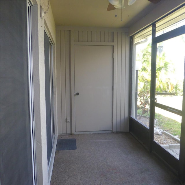 unfurnished sunroom featuring a ceiling fan and a wealth of natural light