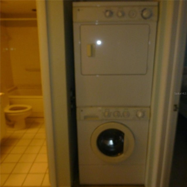 laundry area featuring light tile patterned floors and stacked washer / drying machine