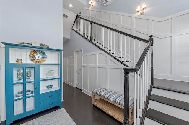 stairway featuring a decorative wall, wood finished floors, and visible vents