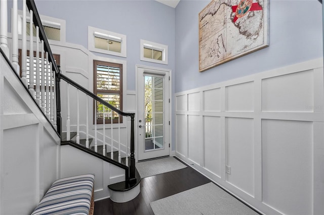 foyer entrance featuring a decorative wall, stairs, a wainscoted wall, and wood finished floors